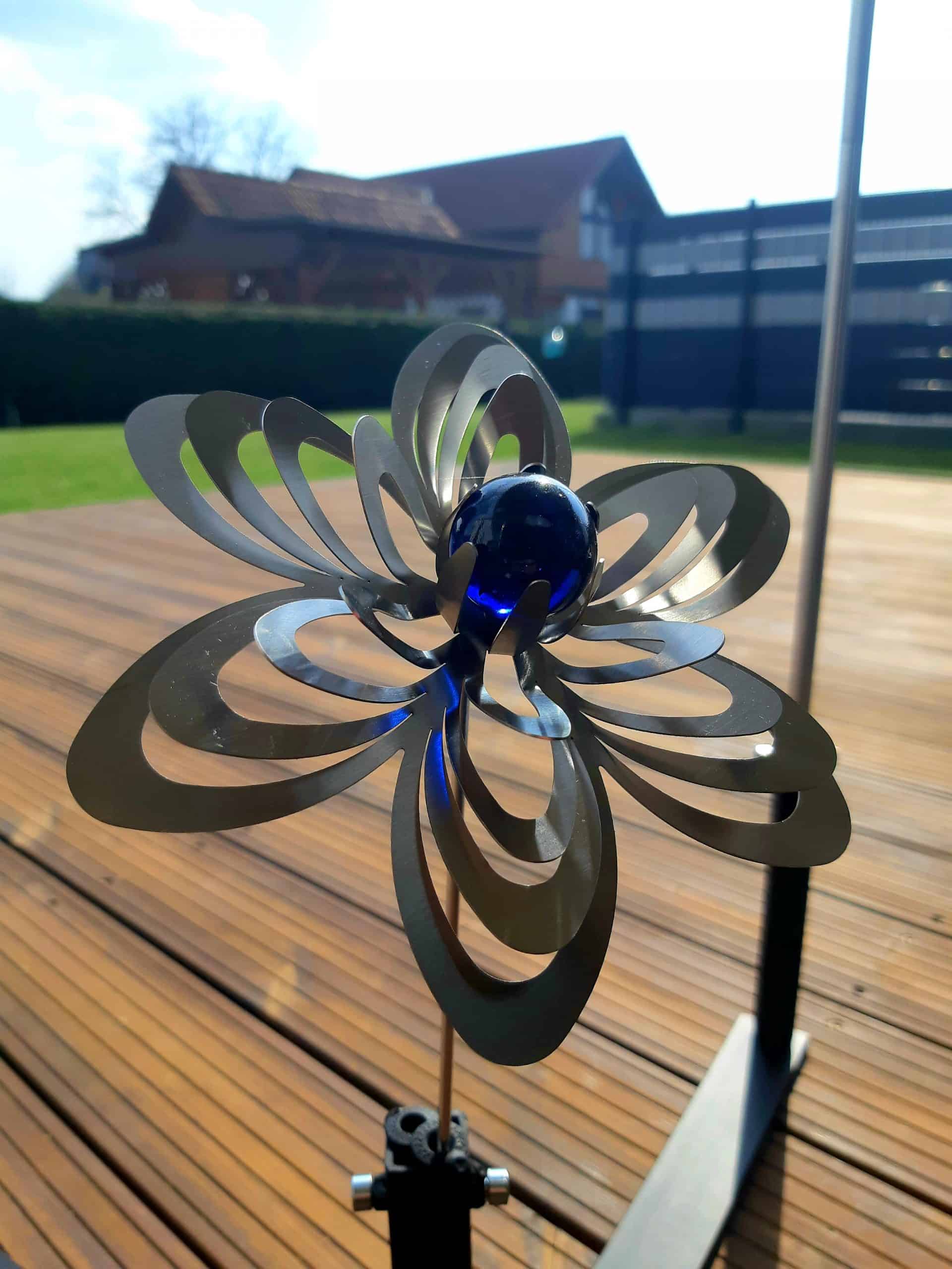 Künstlerisches Metallkunstwerk in Form einer Blumen mit blauer Kristallkugel, ideales Deko-Objekt im Garten.