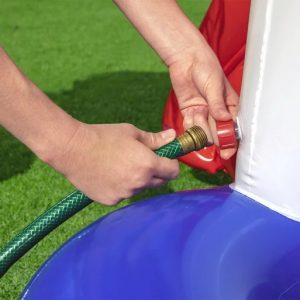 Alt-Text: Person verbindet Gartenschlauch mit Wasserpumpe auf Rasenfläche, Installation.