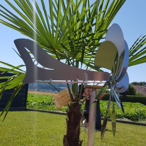 Alt-Text: Metall-Windspiel an einer Palme im Garten, reflektierend und dekorativ.