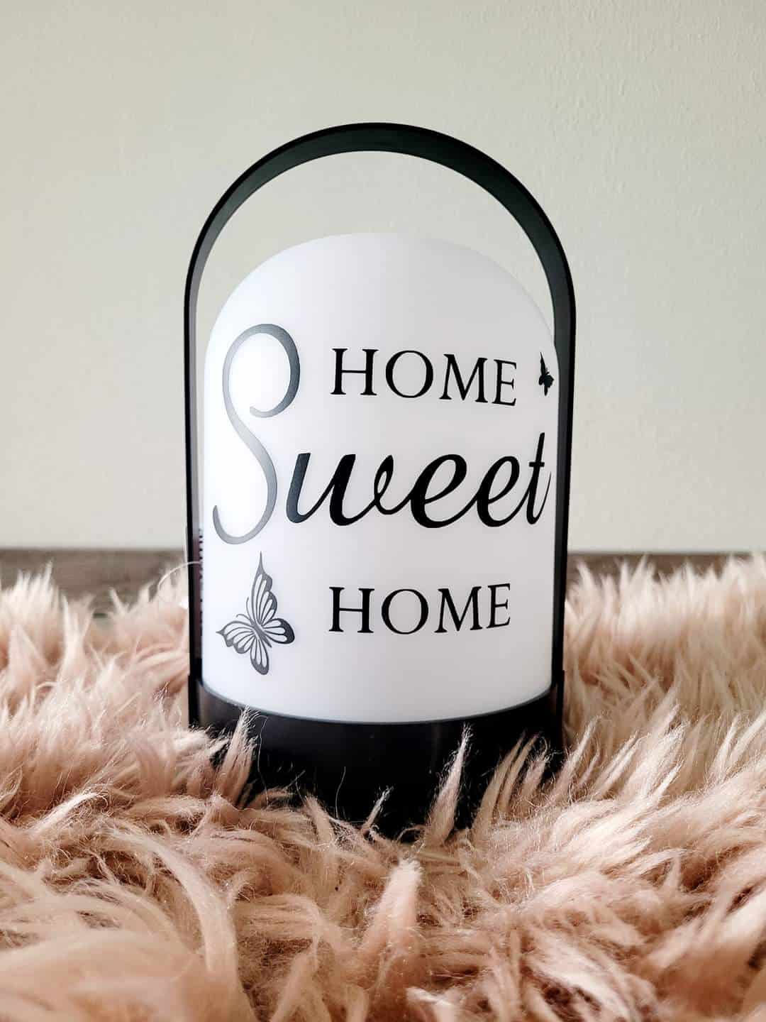 Sommerliche Deko: Kerze mit Motiv "Home Sweet Home" und Schmetterlingsdekor für ein gemütliches Zuhause.